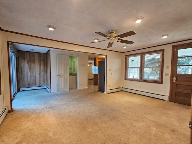 unfurnished room with light carpet, plenty of natural light, baseboard heating, and crown molding