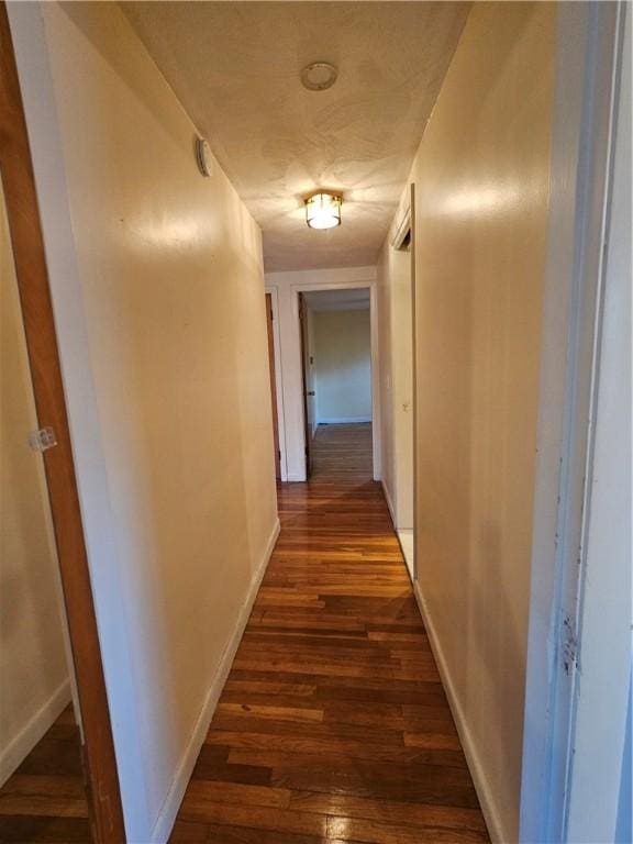 corridor with baseboards and dark wood-type flooring