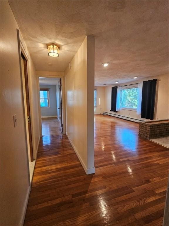 hallway featuring a baseboard heating unit, baseboards, and hardwood / wood-style flooring