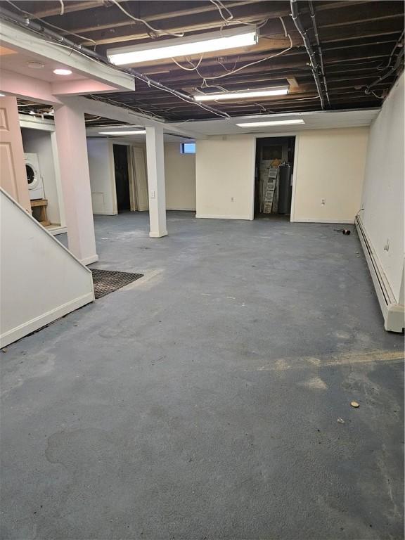 unfinished basement with washer / dryer and a baseboard heating unit