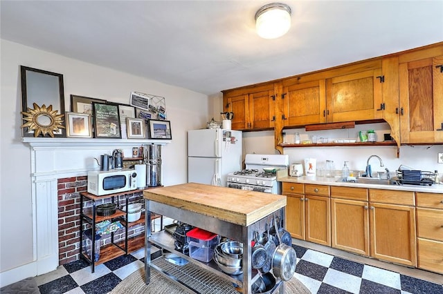 kitchen featuring open shelves, light countertops, a sink, white appliances, and tile patterned floors