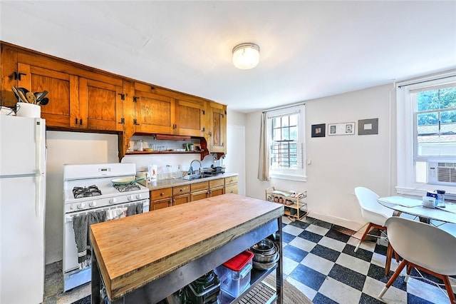 kitchen featuring dark floors, white appliances, a sink, and a wealth of natural light