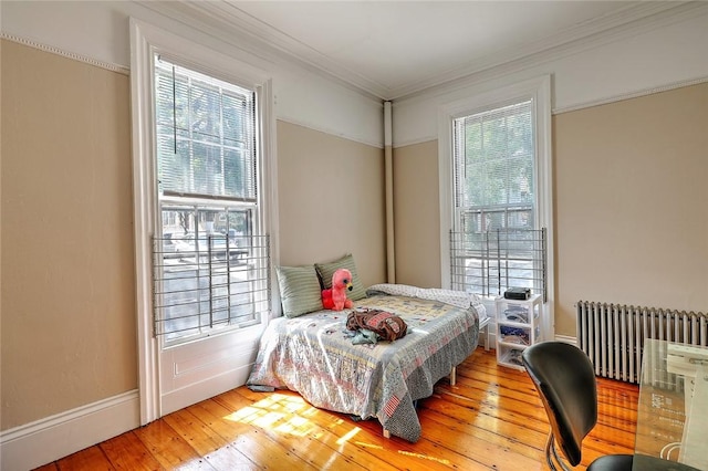 bedroom featuring ornamental molding, radiator heating unit, and wood-type flooring