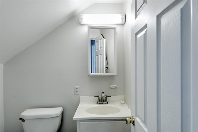 half bath with toilet, vanity, and lofted ceiling