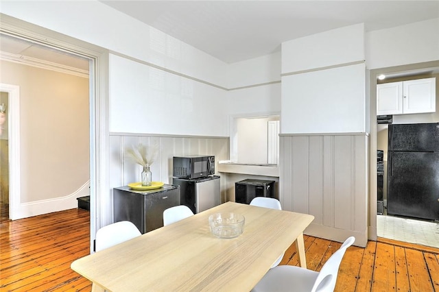 kitchen featuring black appliances, white cabinets, and hardwood / wood-style flooring