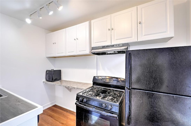 kitchen featuring light wood finished floors, light countertops, white cabinetry, under cabinet range hood, and black appliances