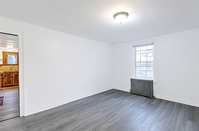 spare room with dark wood-style floors, baseboards, and radiator heating unit