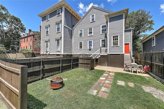 rear view of house with a yard, an outdoor fire pit, entry steps, a patio area, and a fenced backyard