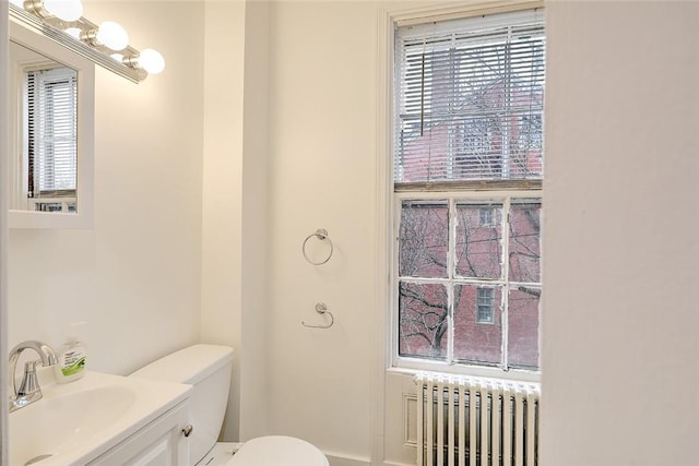 bathroom featuring toilet, vanity, and radiator heating unit