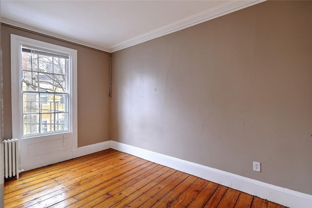 unfurnished room with radiator, light wood-type flooring, crown molding, and a wealth of natural light