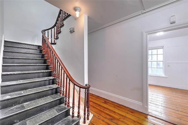 stairway with hardwood / wood-style flooring, baseboards, and ornamental molding