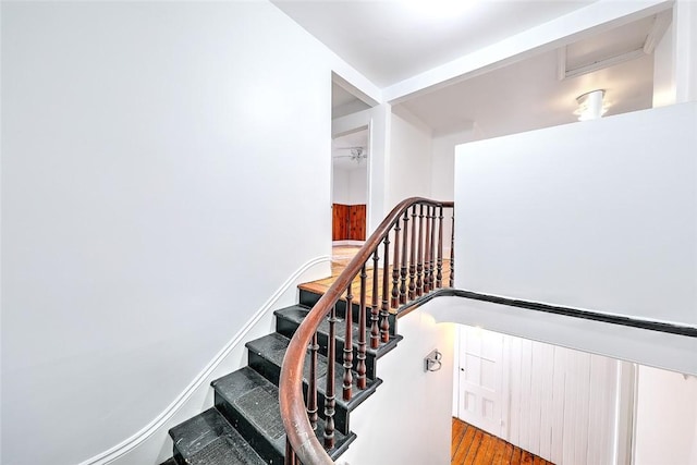 staircase featuring baseboards and wood finished floors