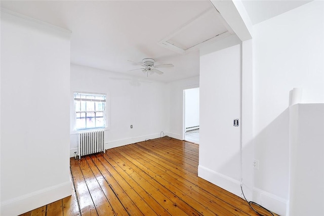 unfurnished room with a ceiling fan, baseboards, light wood-style flooring, and radiator heating unit