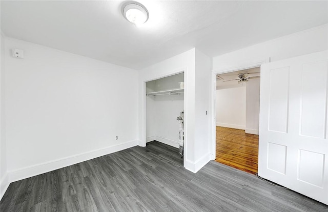 unfurnished bedroom featuring dark wood-type flooring, a closet, and baseboards