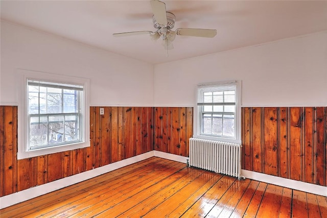 spare room featuring a wainscoted wall, a healthy amount of sunlight, hardwood / wood-style flooring, and radiator