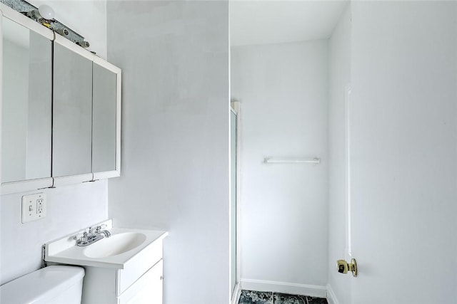 bathroom with toilet, a shower stall, baseboards, and vanity