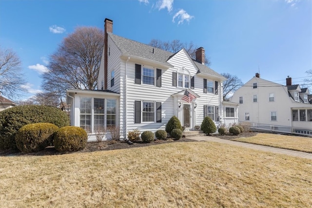 colonial home featuring a chimney and a front lawn