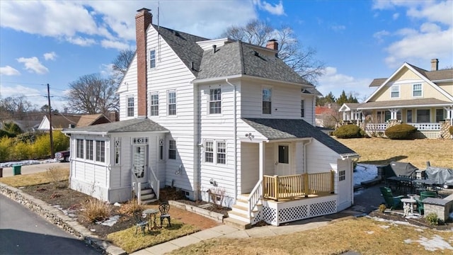 back of house featuring a shingled roof and a chimney