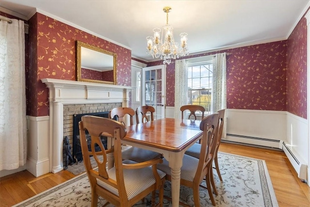 dining area featuring a wainscoted wall, a fireplace, wood finished floors, and wallpapered walls