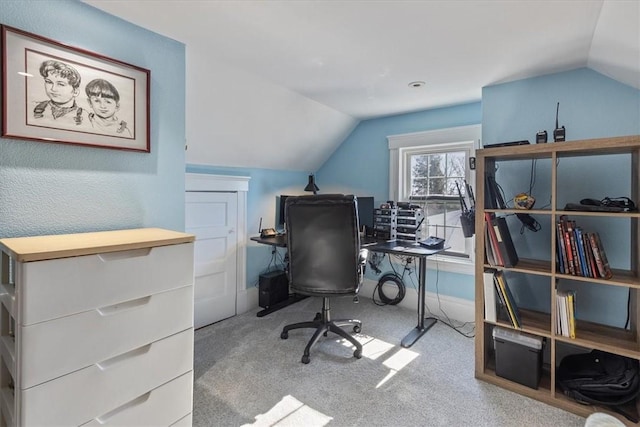 carpeted office space featuring lofted ceiling and baseboards