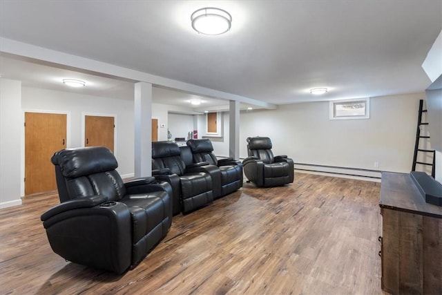 cinema room featuring a baseboard heating unit, baseboards, and wood finished floors