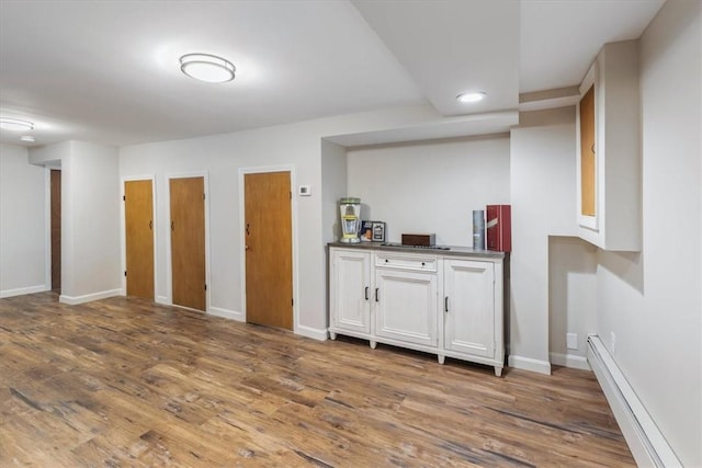 bar with a baseboard heating unit, recessed lighting, wood finished floors, and baseboards