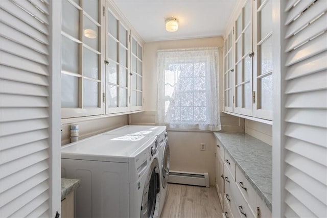 laundry area with light wood-type flooring, baseboard heating, cabinet space, and washing machine and clothes dryer