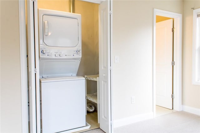 clothes washing area featuring laundry area, baseboards, and stacked washer and clothes dryer