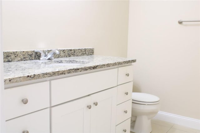 half bath featuring toilet, tile patterned flooring, vanity, and baseboards