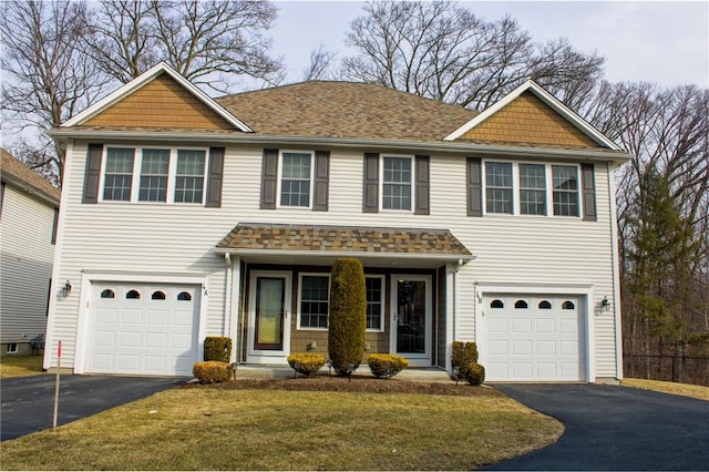 view of front of property featuring aphalt driveway, a front lawn, a shingled roof, and an attached garage