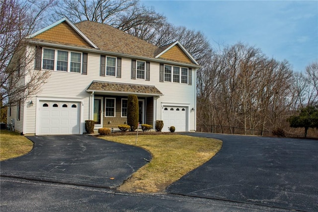 view of front of home with a front lawn, driveway, a shingled roof, and an attached garage