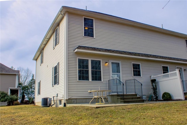 back of property with central AC unit and a yard