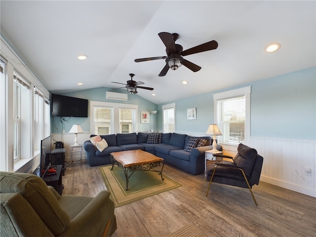 living area featuring lofted ceiling, a wainscoted wall, a healthy amount of sunlight, and a wall mounted AC