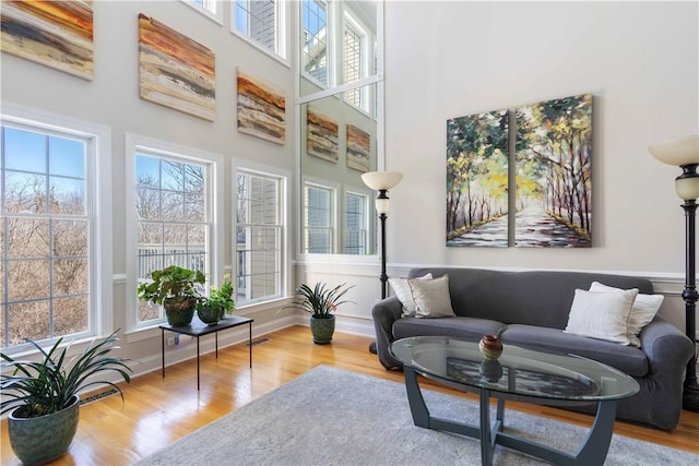 living area featuring baseboards, visible vents, a high ceiling, and wood finished floors