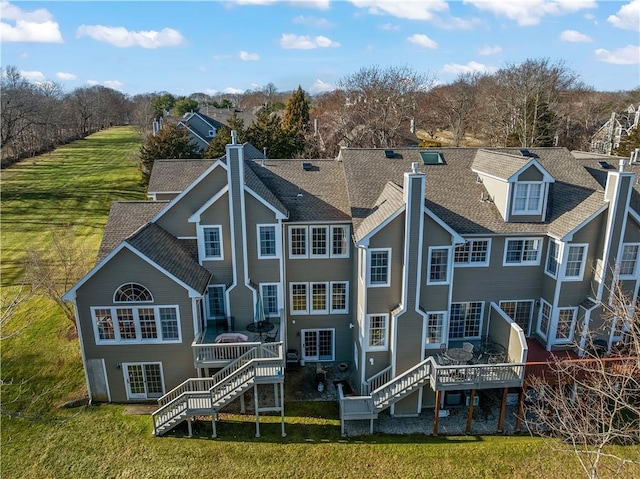 back of property featuring stairs, a yard, a chimney, and a wooden deck