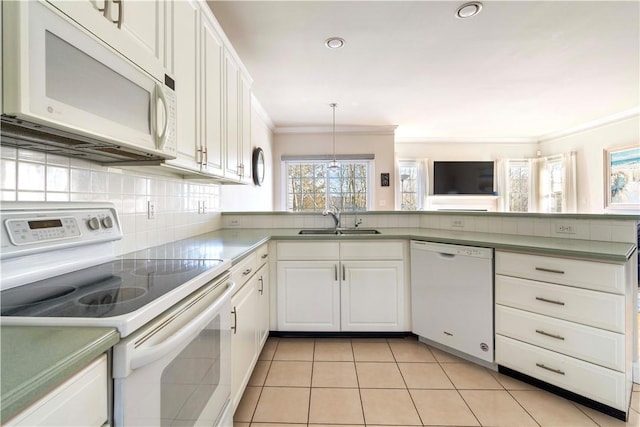 kitchen with white appliances, decorative backsplash, a peninsula, crown molding, and a sink