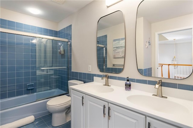 full bath with shower / bath combination with glass door, a sink, toilet, and tile patterned floors