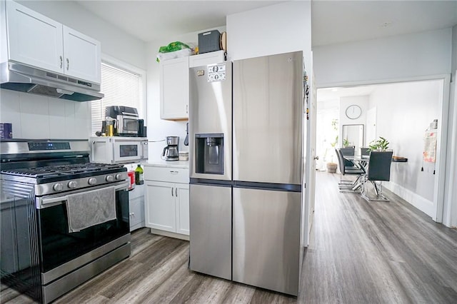 kitchen featuring under cabinet range hood, white cabinetry, appliances with stainless steel finishes, and wood finished floors