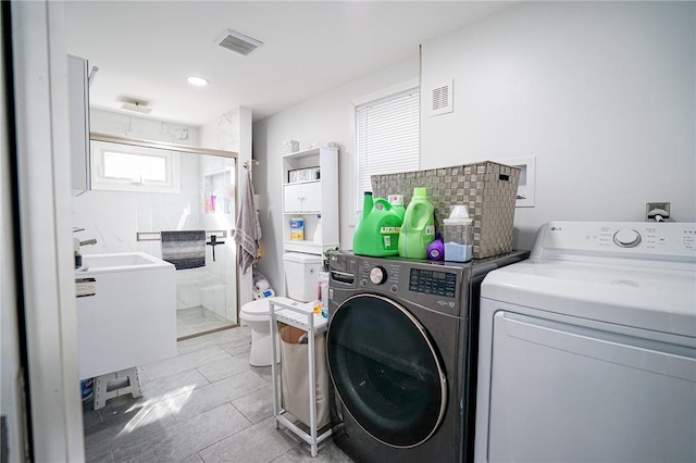 washroom with a sink, laundry area, visible vents, and washer and dryer