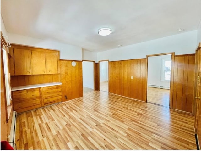 interior space featuring wood walls, light wood-style flooring, and baseboard heating