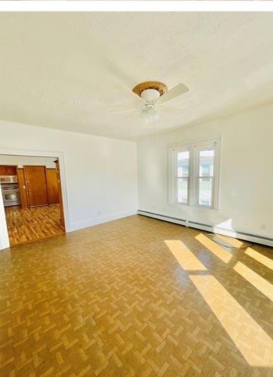 unfurnished room with a ceiling fan, a textured ceiling, and baseboards