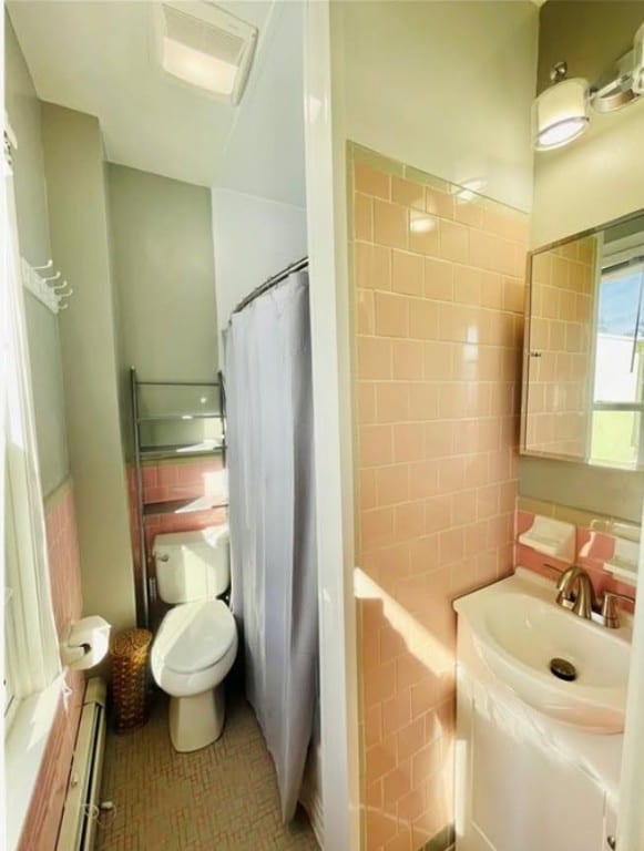 bathroom featuring tile walls, a baseboard radiator, toilet, vanity, and tile patterned flooring