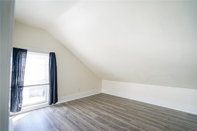 bonus room featuring lofted ceiling, dark wood-type flooring, and baseboards