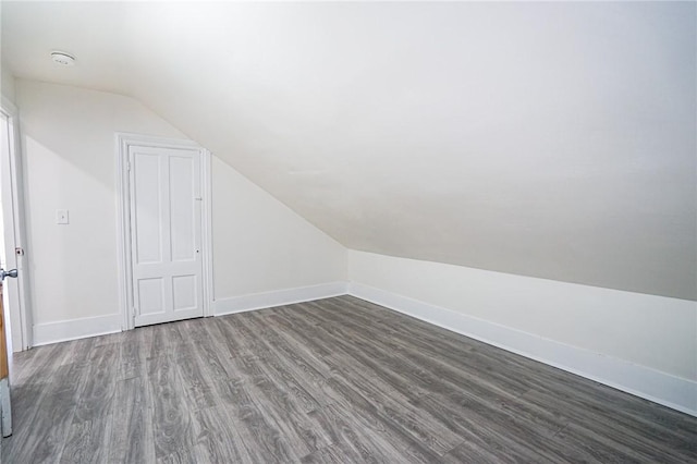 additional living space featuring lofted ceiling, dark wood finished floors, and baseboards