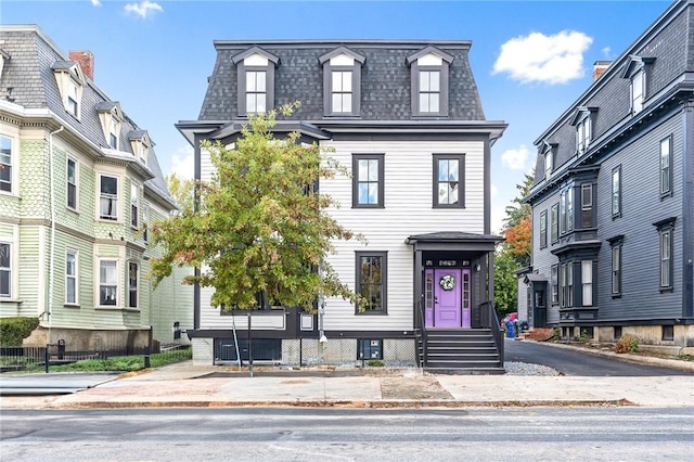 victorian home with roof with shingles, central AC, and mansard roof