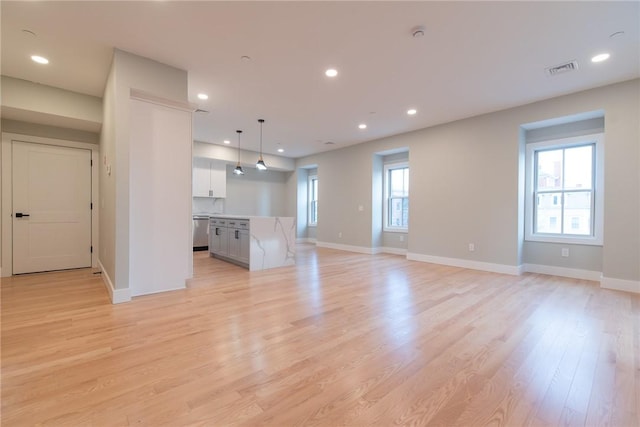 unfurnished living room with a healthy amount of sunlight, light wood finished floors, visible vents, and recessed lighting