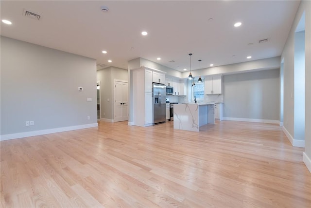 kitchen with visible vents, light wood-style flooring, a breakfast bar, open floor plan, and stainless steel appliances