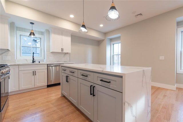 kitchen featuring a kitchen island, light wood-style floors, decorative backsplash, dishwasher, and gas range oven