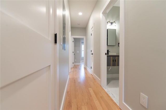 hallway featuring light wood-style flooring and baseboards