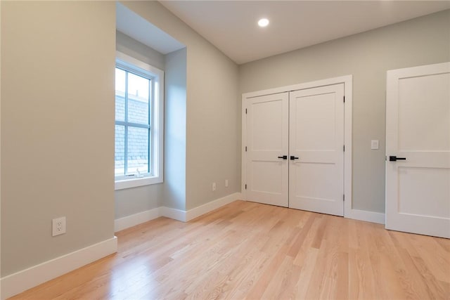 unfurnished bedroom featuring light wood-style flooring, baseboards, a closet, and recessed lighting